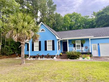 Charming blue home with a manicured front yard and a mature palm tree, showcasing curb appeal at 1325 Edward Dr, Moncks Corner, SC 29461