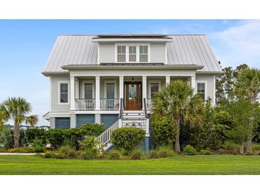 Charming two-story home featuring a metal roof, elevated porch, and manicured landscaping at 1500 Bower Ln, Johns Island, SC 29455