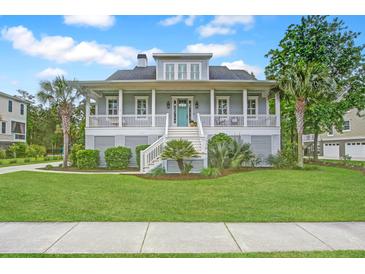 Inviting two-story home featuring a spacious front porch, well-manicured lawn, and lush tropical landscaping at 1776 W Canning Dr, Mount Pleasant, SC 29466