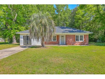 Charming brick home with a lush green lawn and a mature palm tree in the front yard at 2736 Shadow Ln, North Charleston, SC 29406