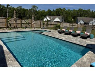 Sparkling blue swimming pool with lounge chairs and lush landscaping in a private backyard setting at 3173 Hugh Bennett Dr, Johns Island, SC 29455