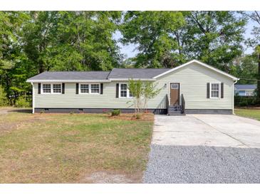 Charming single-story home with light green siding, dark trim, a gray roof, and a mix of gravel and concrete driveway at 5774 Scott White Rd, Hollywood, SC 29449
