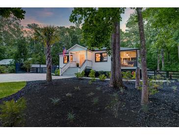 Charming home featuring manicured landscaping, a palm tree, and a cozy front porch with an American flag at 128 Paul Dr, Summerville, SC 29483