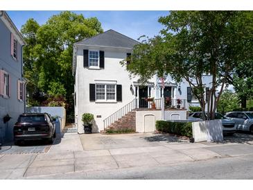 Charming two-story home with a white exterior, black shutters, and a beautifully landscaped front yard at 19 Ashley Ave, Charleston, SC 29401