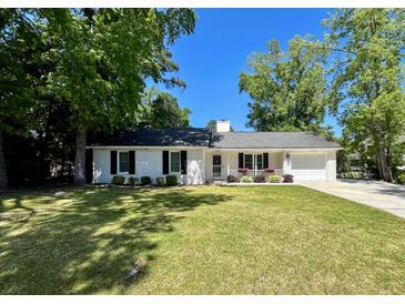 Charming single-story home with a well-manicured lawn, mature trees, and a welcoming front porch at 1534 Kentwood Cir, Charleston, SC 29412
