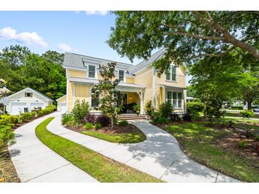Charming two-story home with yellow siding, lush landscaping, and a curved driveway at 3413 Acorn Drop Ln, Johns Island, SC 29455