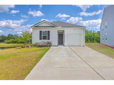 Charming single-story home with well-manicured lawn, pond view, and attached garage at 1011 Peridote Way, Ladson, SC 29456