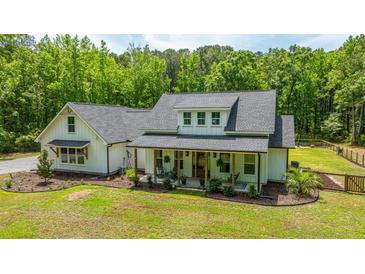 Charming white farmhouse-style home with a welcoming front porch and lush green lawn at 1375 Tannanger Trl, Awendaw, SC 29429