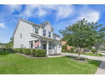 Charming two-story home with a well-manicured lawn, inviting porch, and an American flag waving in the breeze at 246 Calm Water Way, Summerville, SC 29486