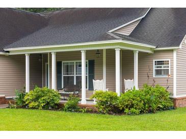 Inviting covered porch with rocking chairs and lush landscaping offers a relaxing outdoor space at 3113 Edenvale Rd, Johns Island, SC 29455