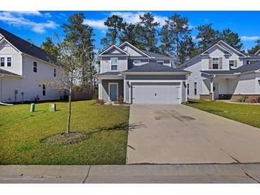 Charming two-story home with gray siding, an attached garage, a well-manicured lawn, and lush, mature trees at 164 Wappoo Trace Ln, Summerville, SC 29486