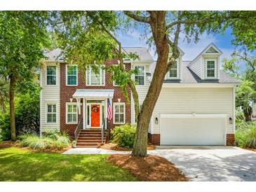 Charming two-story home featuring a brick facade, siding, a welcoming orange front door, and lush landscaping at 174 Revetment Ln, Mount Pleasant, SC 29464