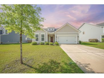Charming single-story home featuring a well-manicured lawn and a two-car garage, complemented by mature landscaping at 311 Beachgrass Ln, Summerville, SC 29486