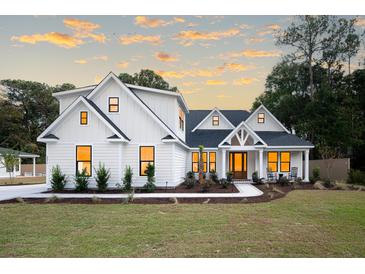 Beautiful two-story home featuring a pristine green lawn and attractive landscaping at sunset at 477 Yellow House Pl, Charleston, SC 29492