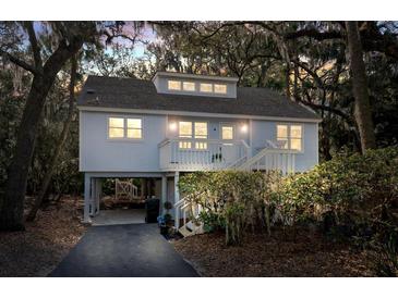 Charming coastal home with a inviting porch, staircase, and an elevated foundation amidst lush foliage at 555 Double Eagle, Seabrook Island, SC 29455