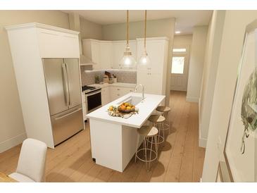 Bright kitchen features white cabinetry, stainless steel appliances, and a center island with bar stool seating at 7423 Indigo Palms Way, Johns Island, SC 29455