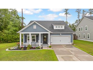 Charming blue home featuring a well-manicured lawn and a cozy front porch with rocking chairs at 148 Haverhill St, Summerville, SC 29486