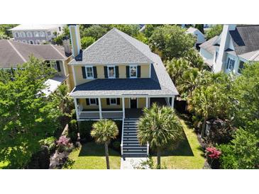 Charming two-story yellow home with lush landscaping and a welcoming front porch at 2449 Daniel Island Dr, Daniel Island, SC 29492