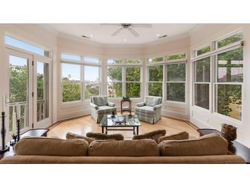 Bright living room featuring expansive windows, a ceiling fan, and comfortable seating for relaxing and enjoying the natural light at 26 Beachwood East, Isle of Palms, SC 29451