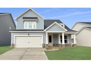 Charming two-story home with light blue siding, a white garage door, and a well-manicured lawn at 459 White Magnolia St, Moncks Corner, SC 29461