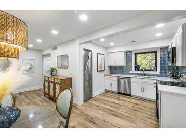 Bright kitchen features stainless steel appliances, white cabinetry, and stylish blue tile backsplash at 153 High Hammock Villas, Seabrook Island, SC 29455
