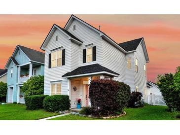 Charming two-story white home with black shutters, lush landscaping, and inviting curb appeal against a colorful evening sky at 221 Trillium Ave, Summerville, SC 29483