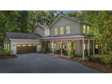 Beautiful two-story home with a covered front porch, two-car garage, and a gravel driveway surrounded by mature trees at 32 Middleton Oaks Rd, Charleston, SC 29414