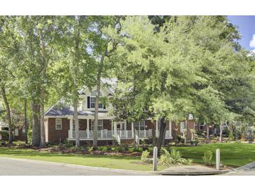 Charming two-story home with red brick and white trim, featuring a welcoming front porch and lush landscaping at 4217 Meadowbrook Ct, North Charleston, SC 29420