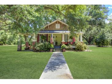 Charming home featuring a well-manicured lawn, inviting porch, and beautiful mature trees at 5126 Highway 174, Hollywood, SC 29449