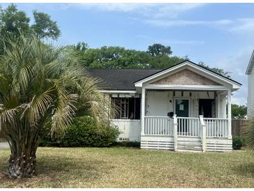Exterior view of a white one-story home with a porch, in need of renovation at 650 Atlantic St, Mount Pleasant, SC 29464