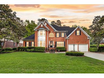 Beautiful two-story brick home with manicured lawn, black shutters, mature trees and two-car garage at 8662 W Fairway Woods Dr, North Charleston, SC 29420