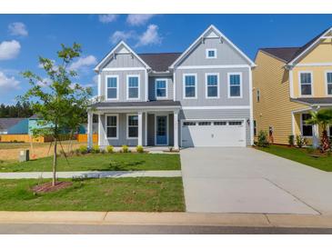 Charming two-story home with a well-manicured lawn, attached garage, and inviting blue door at 1215 Homecoming Blvd # Cc2-1-25, Ravenel, SC 29470