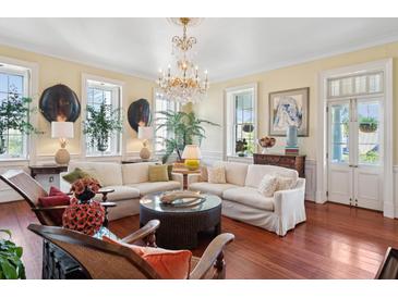 Bright living room featuring a chandelier, white sofa, wood floors, and large windows at 5 Legare St # C, Charleston, SC 29401