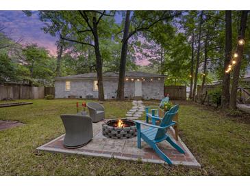 Charming backyard with a fire pit, Adirondack chairs, and well-maintained lawn offers an ideal spot for outdoor relaxation at 825 Savage Rd, Charleston, SC 29414