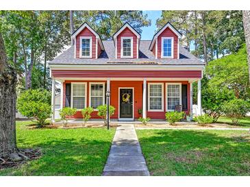 Charming two-story red home featuring a well-manicured lawn and inviting front porch at 8965 N Red Maple Cir, Summerville, SC 29485