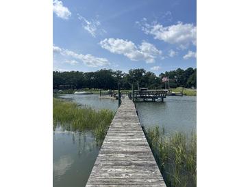 Scenic waterfront view showcasing a private wooden dock and pier with a charming seating area under a cloudy sky at 932 N Shem Dr, Mount Pleasant, SC 29464