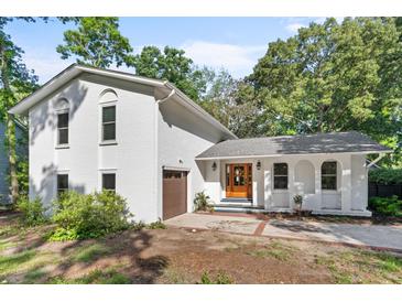 Charming painted brick home featuring a beautiful wood front door and attached garage surrounded by mature trees at 1055 Royalist Rd, Mount Pleasant, SC 29464