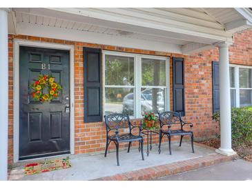 Charming brick condo features a cozy front porch with chairs and a welcoming floral wreath on the front door at 1816 Mepkin Rd # B1, Charleston, SC 29407