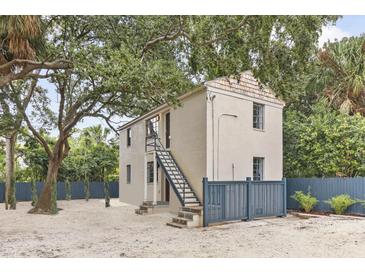 Charming home featuring a stucco exterior, inviting entrance stairs, and a privacy fence, all nestled under mature trees at 19 Smith St # C, Charleston, SC 29401