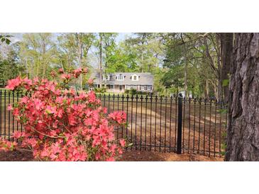 Picturesque home with beautiful landscaping and a black fence, blending elegance with natural charm for an inviting curb appeal at 206 Chaussee Blvd, Summerville, SC 29483