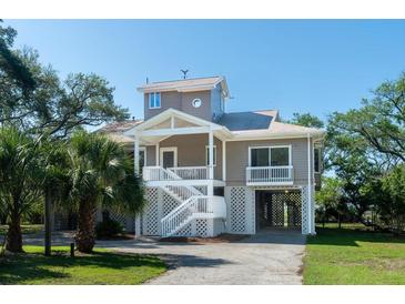 Inviting coastal home with a raised foundation, covered parking, and charming beachside appeal with lush landscaping at 1195 Framptons Inlet Rd, Edisto Island, SC 29438