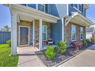 Charming front porch with stone accents, seating, and landscaped garden bed, exuding curb appeal at 175 Darby Meadow Ln, Ridgeville, SC 29472