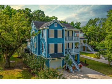 Charming two-story blue home featuring a double porch, lush landscaping, and a garage at 3711 Tip Ln, Mount Pleasant, SC 29466