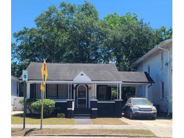 Charming single-story home with black and white trim, a covered porch, and a driveway with parking at 932 Rutledge Ave, Charleston, SC 29403