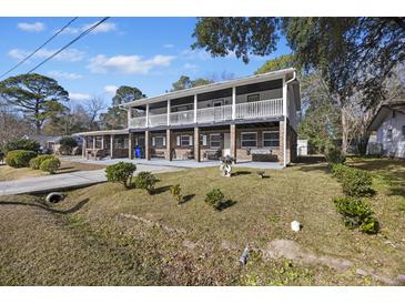 Two-story brick home featuring double balconies, a well-manicured lawn, and mature trees in a residential neighborhood at 1520 Acacia St, Charleston, SC 29407