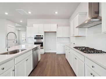 Bright kitchen features white cabinets, stainless steel appliances, a large island with sink, and hardwood floors at 211 Yalton St, Summerville, SC 29486