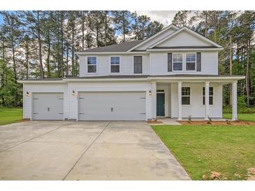 New two-story home boasts white siding, dark shutters, and a spacious three-car garage in a wooded area at 5182 Stono Plantation Rd Dr, Hollywood, SC 29449