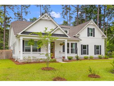 Charming two-story home featuring a inviting front porch, manicured lawn and attractive landscaping at 727 Hodge Rd, Summerville, SC 29483