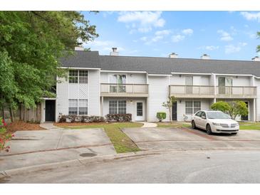 View of townhomes featuring balconies, trimmed bushes, and individual parking spots at 7813 Sandida Ct, North Charleston, SC 29418