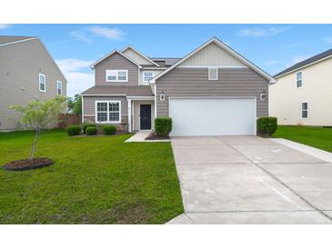 Two-story home features manicured lawn, neutral siding, stone accents, and attached two-car garage at 9711 Tackle St, Ladson, SC 29456